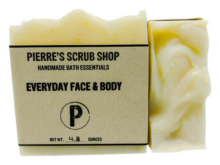 An Everyday Face & Body bar in its kraft paper wrapper beside an unwrapped cream swirled bar